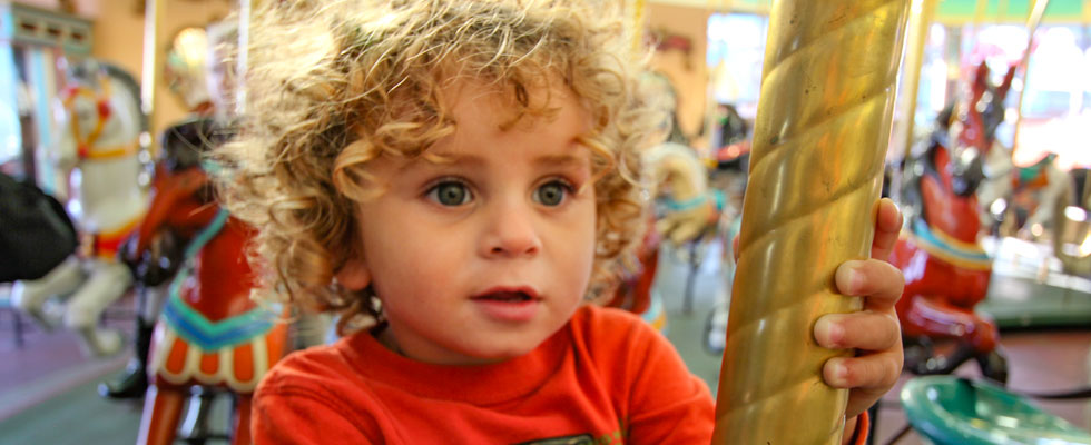 Young Child With Curly Hair In The Carousel